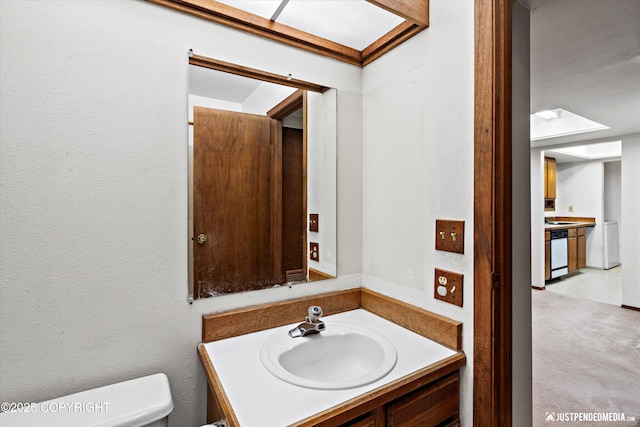 bathroom with a textured wall, vanity, and toilet