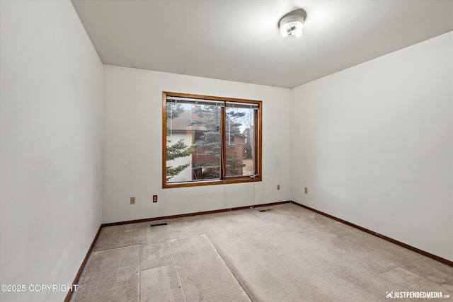 empty room featuring carpet flooring, visible vents, and baseboards