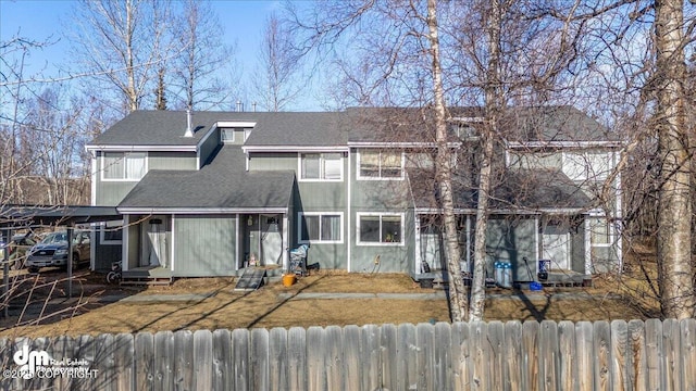 back of house featuring entry steps, roof with shingles, and fence