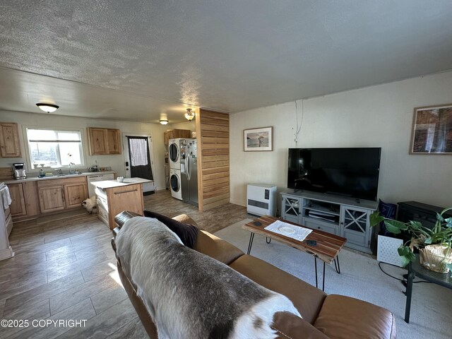 living area with a textured ceiling, stacked washer and dryer, and heating unit