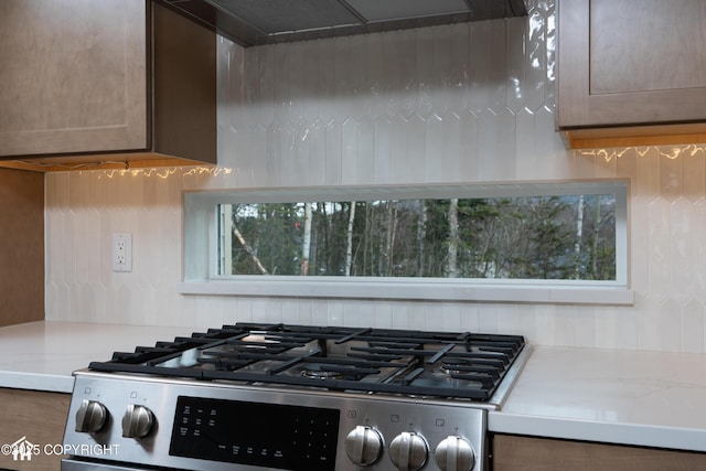 kitchen featuring stainless steel gas range, extractor fan, and light countertops