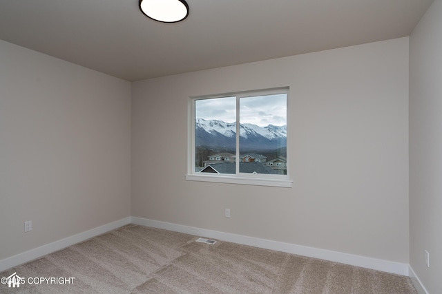 spare room featuring carpet, visible vents, baseboards, and a mountain view