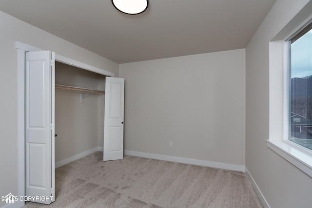 unfurnished bedroom with baseboards, a closet, and light colored carpet