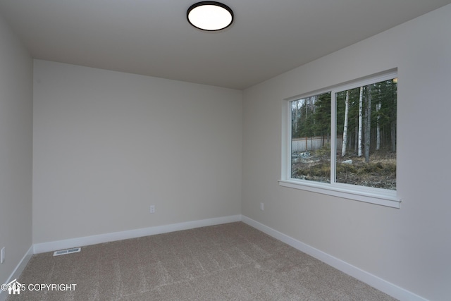 unfurnished room featuring carpet, visible vents, and baseboards