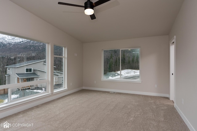 carpeted spare room with vaulted ceiling, ceiling fan, and baseboards