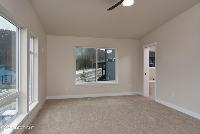 empty room with lofted ceiling, visible vents, carpet flooring, ceiling fan, and baseboards