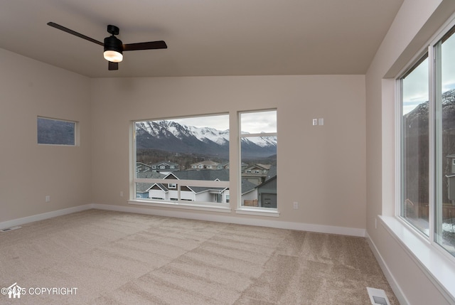 empty room with baseboards, visible vents, lofted ceiling, ceiling fan, and carpet flooring