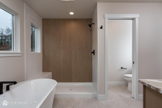 full bathroom featuring toilet, vanity, a shower stall, a freestanding tub, and tile patterned floors