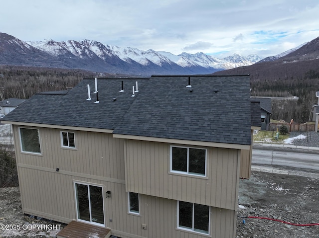 back of house with a mountain view and roof with shingles