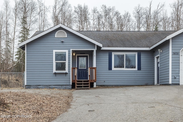 ranch-style home featuring fence, driveway, and a shingled roof