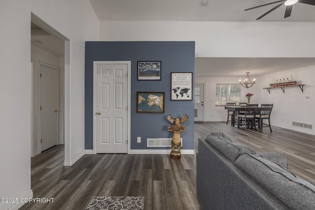 living room featuring dark wood-style floors, visible vents, and ceiling fan with notable chandelier