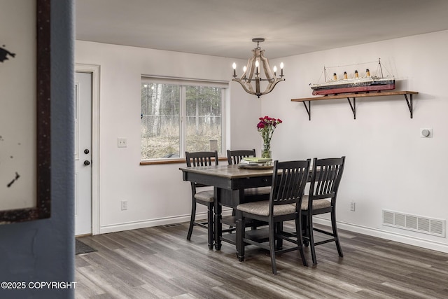 dining area featuring baseboards, a chandelier, dark wood-type flooring, and visible vents