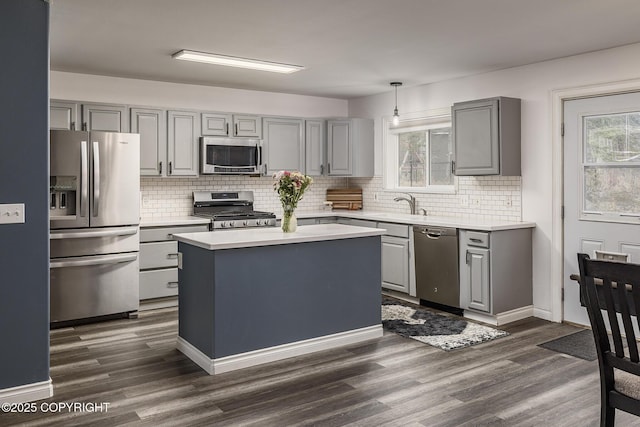 kitchen featuring gray cabinets, light countertops, backsplash, appliances with stainless steel finishes, and dark wood-type flooring