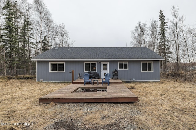 back of house with fence, roof with shingles, and a deck