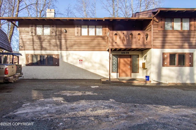 back of house featuring a chimney and stucco siding