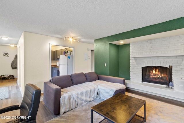 living room featuring a textured ceiling, a fireplace, and wood finished floors