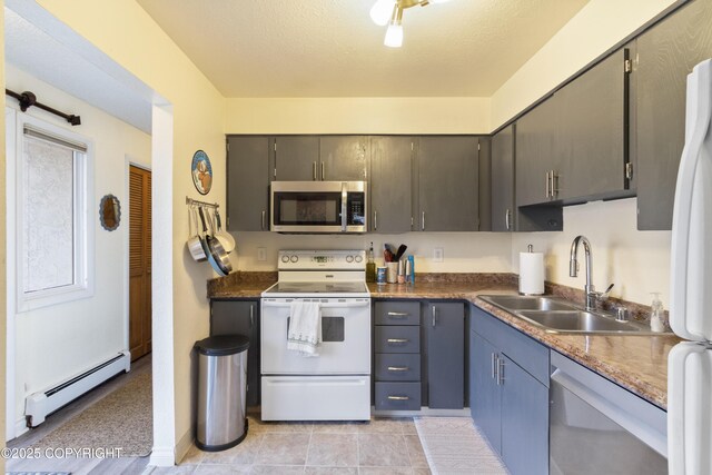 kitchen featuring dark countertops, baseboard heating, stainless steel appliances, and a sink