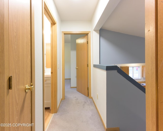 corridor featuring light carpet, baseboards, and an upstairs landing