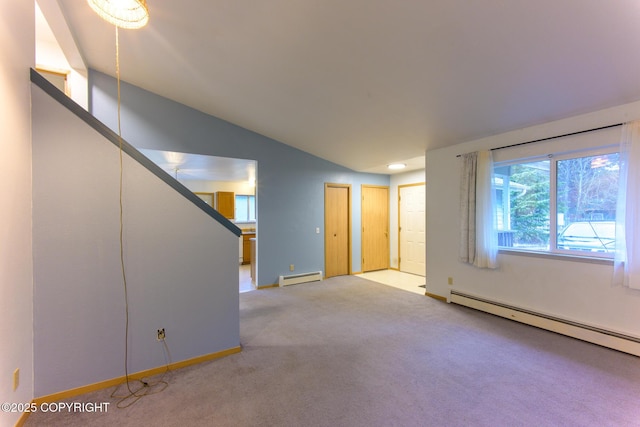 spare room with a baseboard radiator, light carpet, vaulted ceiling, and baseboards