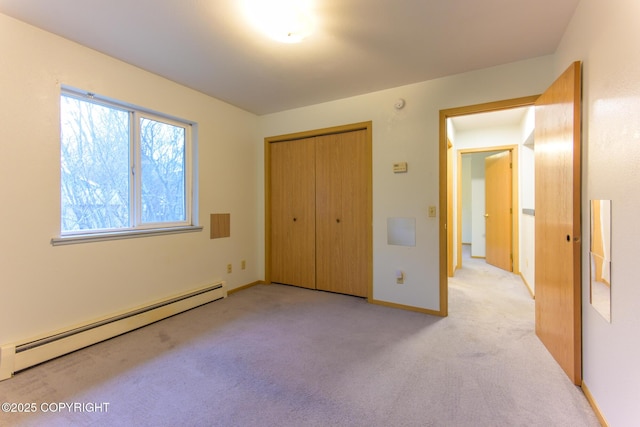 unfurnished bedroom featuring a baseboard heating unit, a closet, baseboards, and light colored carpet