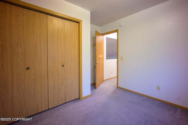 unfurnished bedroom with carpet floors, a closet, and baseboards