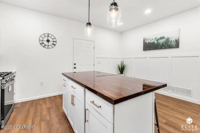 kitchen with gas stove, wood finished floors, a kitchen bar, and a decorative wall