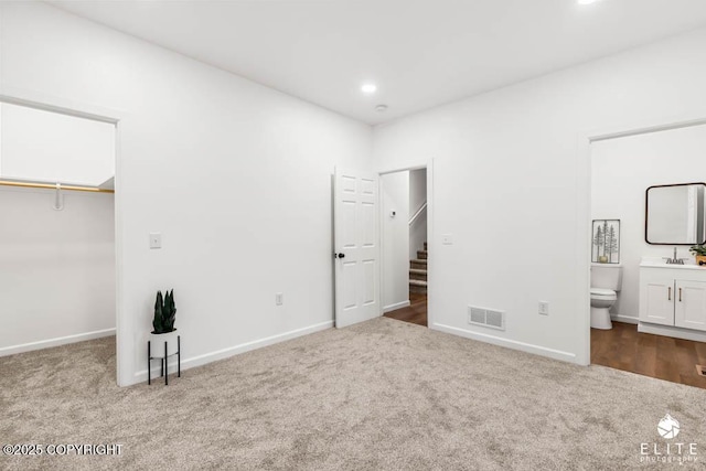 unfurnished bedroom featuring visible vents, a spacious closet, carpet flooring, and ensuite bathroom