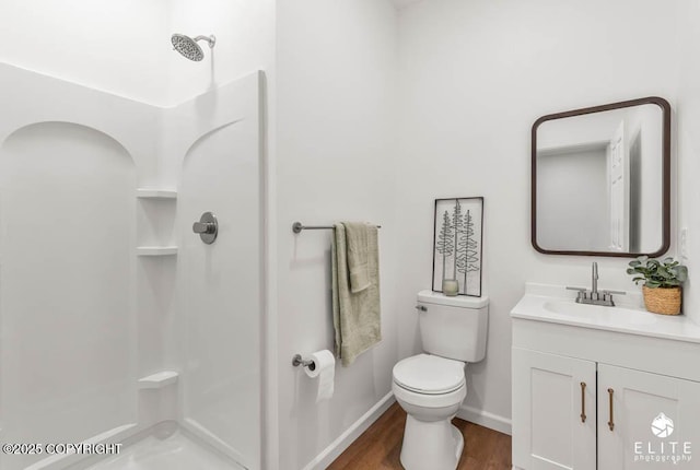 bathroom with wood finished floors, vanity, toilet, and a walk in shower