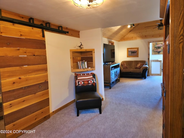 living area featuring a barn door, baseboards, vaulted ceiling, and carpet flooring