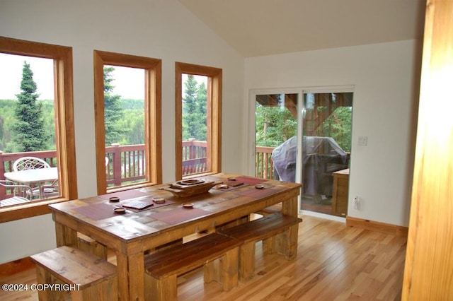 dining room featuring vaulted ceiling, light wood-style flooring, and baseboards