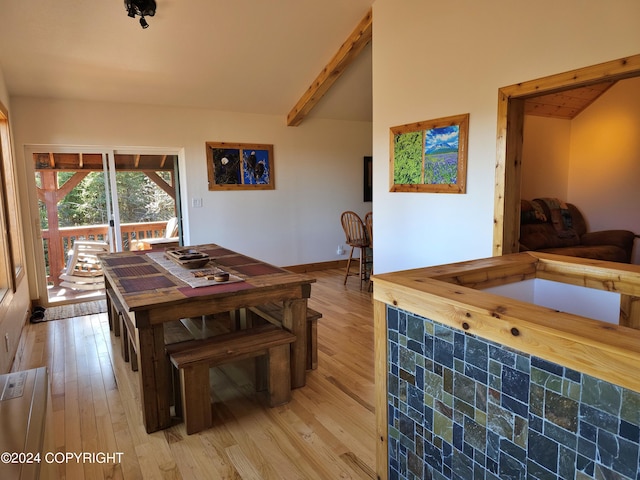 dining room with vaulted ceiling with beams and light wood finished floors