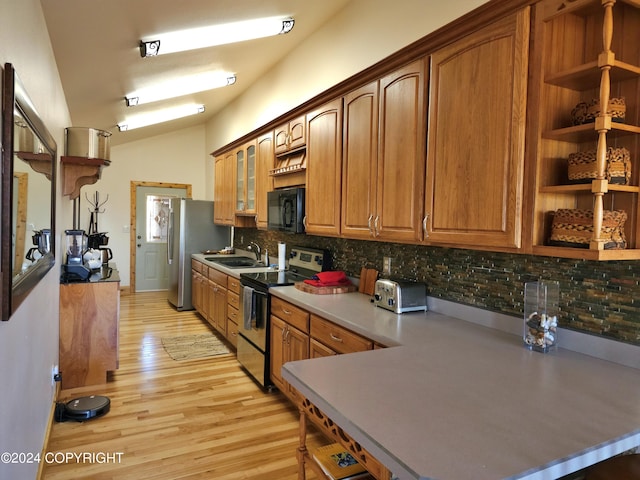 kitchen featuring a sink, vaulted ceiling, appliances with stainless steel finishes, open shelves, and brown cabinetry