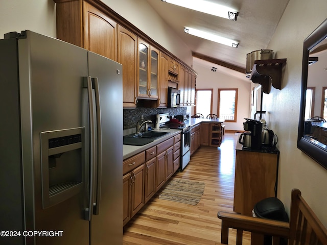 kitchen featuring range with electric cooktop, stainless steel fridge with ice dispenser, glass insert cabinets, vaulted ceiling, and a sink