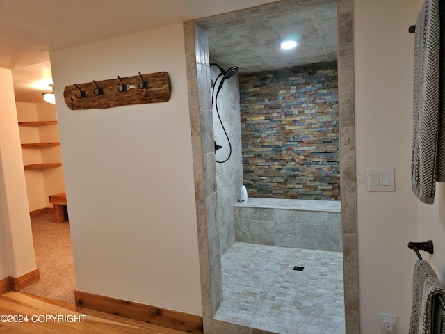 bathroom featuring wood finished floors, walk in shower, and baseboards