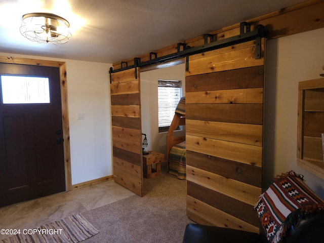 foyer with light carpet, a barn door, baseboards, and a wealth of natural light