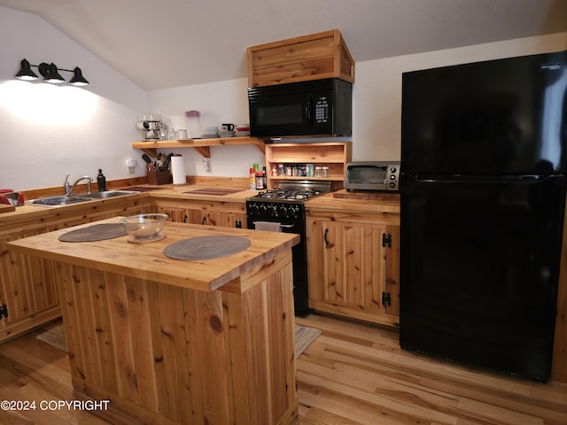 kitchen featuring wood counters, a kitchen island, vaulted ceiling, black appliances, and a sink