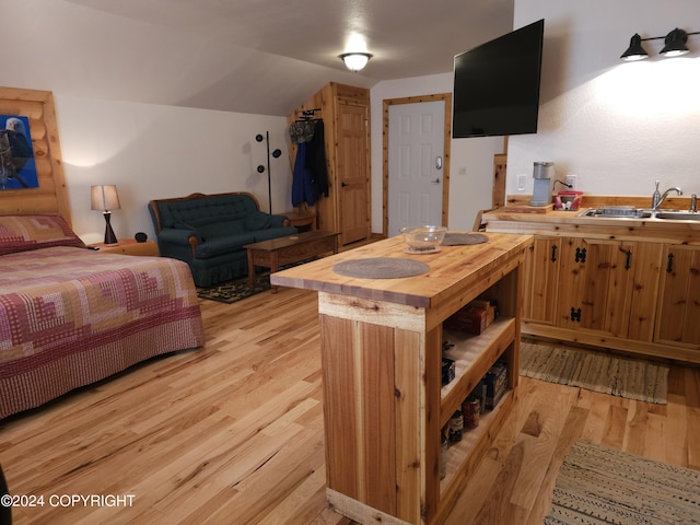 bedroom featuring light wood-type flooring, a sink, and lofted ceiling