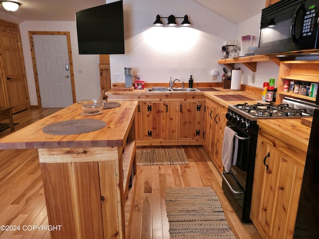 kitchen with black appliances, butcher block counters, light wood finished floors, and a sink