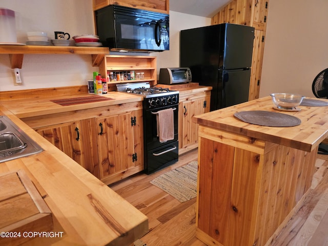 kitchen featuring butcher block countertops, light wood-style floors, black appliances, and open shelves