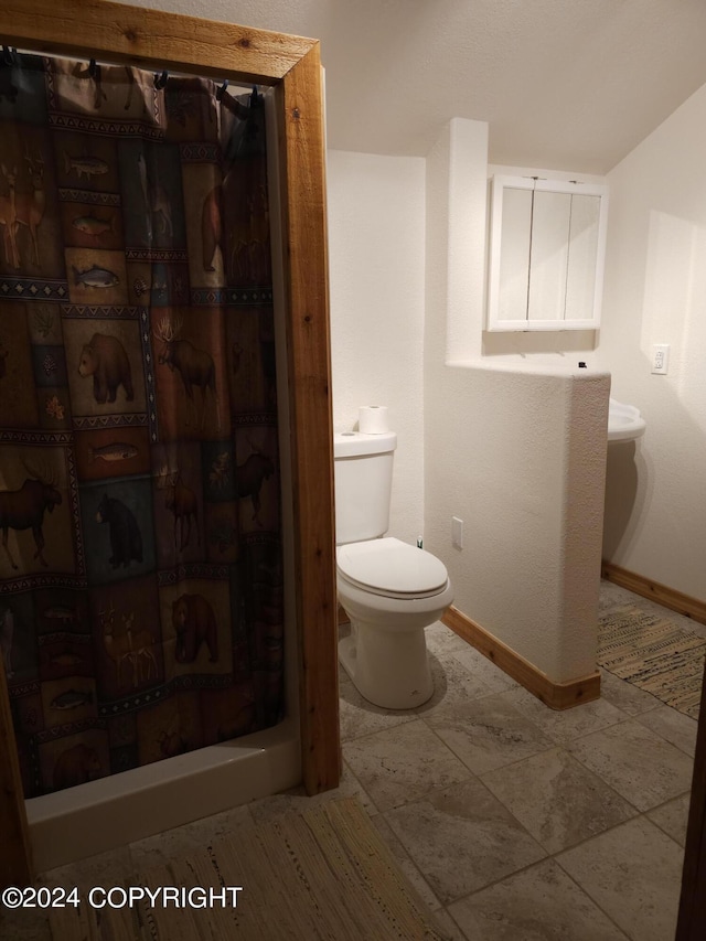 bathroom featuring curtained shower, toilet, and baseboards