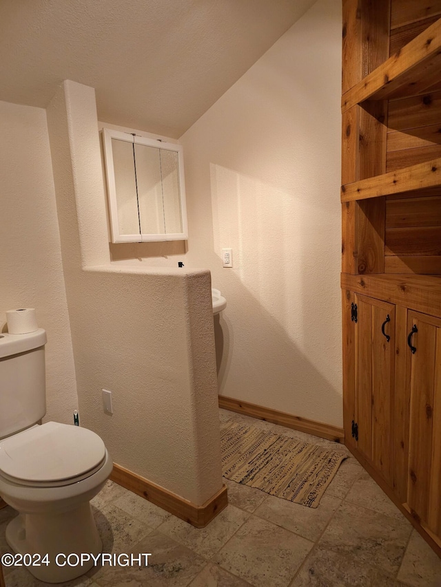 half bathroom with toilet and baseboards