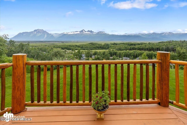 wooden deck with a mountain view and a lawn