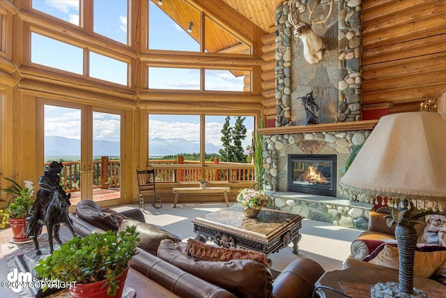 living room with wood ceiling, log walls, a stone fireplace, high vaulted ceiling, and a mountain view