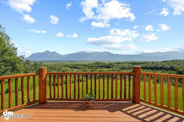 deck featuring a lawn, a wooded view, and a mountain view