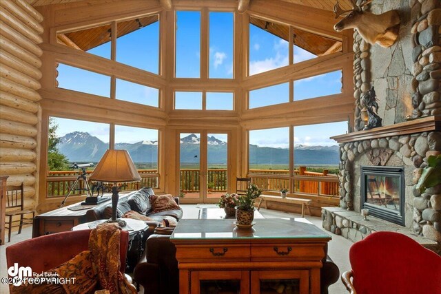 sunroom featuring lofted ceiling, a mountain view, and a stone fireplace