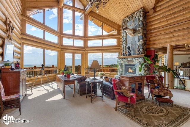 sunroom / solarium with wood ceiling, a mountain view, vaulted ceiling, and a stone fireplace