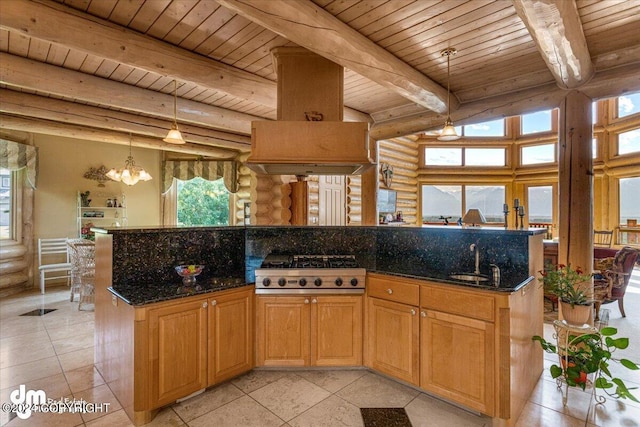 kitchen with dark stone countertops, a center island, stainless steel gas stovetop, pendant lighting, and a sink