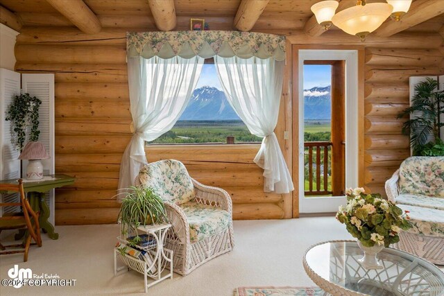 living area with carpet, beam ceiling, log walls, wood ceiling, and a mountain view