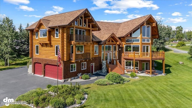 exterior space with a balcony, a garage, driveway, a lawn, and log exterior