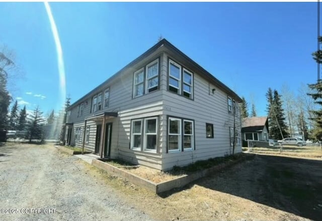 view of side of property with dirt driveway